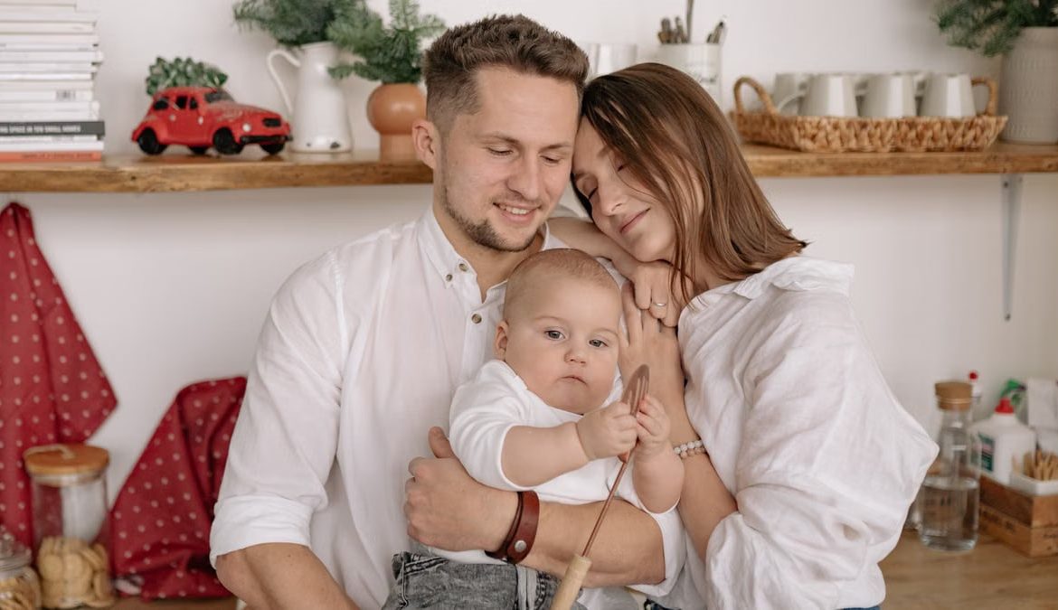 A joyful family of three embracing in a cozy kitchen. Warm and loving atmosphere.